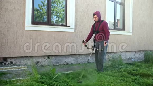 盖伊园丁用汽油割草机割草下午房子附近视频的预览图