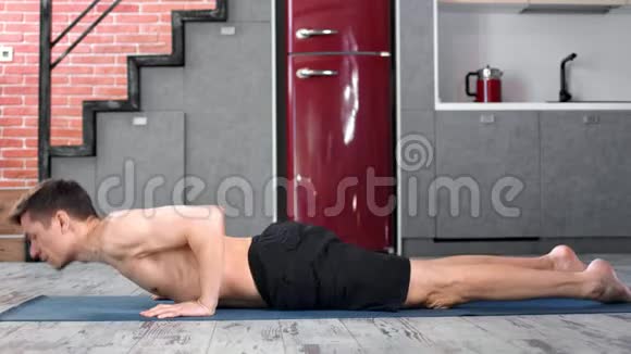 灵活的瑜伽男练习眼镜蛇的位置在垫子在家庭厨房侧视视频的预览图