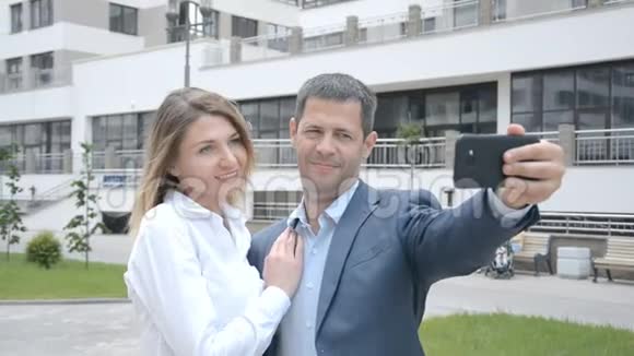 男女商业伙伴与智能手机站在城市自拍视频的预览图