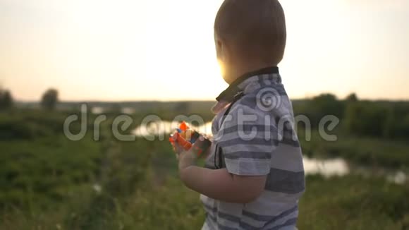 一个可爱的优雅男孩在日落时慢动作地玩拖拉机视频的预览图