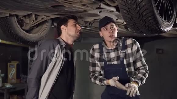 英俊的汽车修理技师向他展示了汽车的主要问题视频的预览图