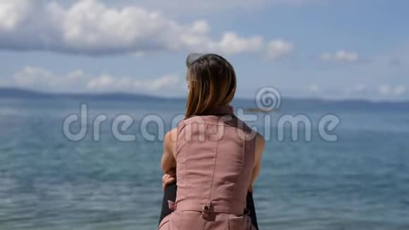 从一个年轻女子的身后看她在海边享受时光视频的预览图