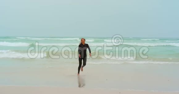 活跃的非裔美国女性冲浪者在海滩上奔跑的正面景色视频的预览图