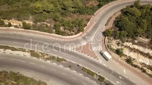在一条弯弯曲曲的小高速公路上飞行周围有一座桥和绿树视频的预览图