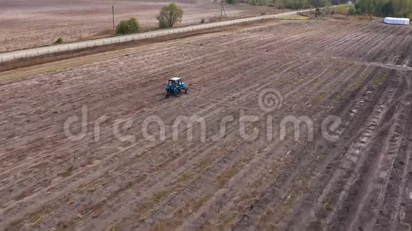 一辆拖拉机在秋天犁田准备过冬的土地空中镜头视频的预览图