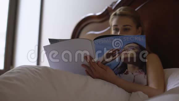 年轻女性在床上阅读女性杂志闲暇时间和放松视频的预览图