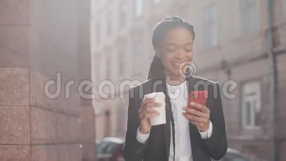 一位身穿西装的年轻非裔美国女商人的肖像在市中心附近散步喝酒视频的预览图