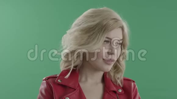 年轻的金发女郎穿着红色夹克在绿色屏幕上显得可爱视频的预览图