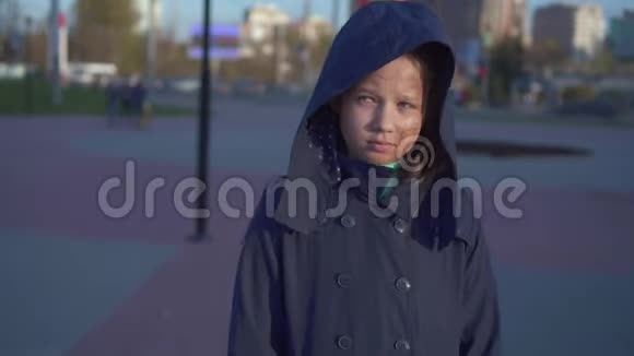焦虑的少女有缺陷或脸烧伤在街上戴着兜帽在城市里走来走去视频的预览图