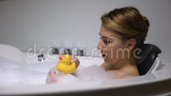 微笑的女人在洗澡时玩橡皮鸭孩子气玩得开心视频的预览图