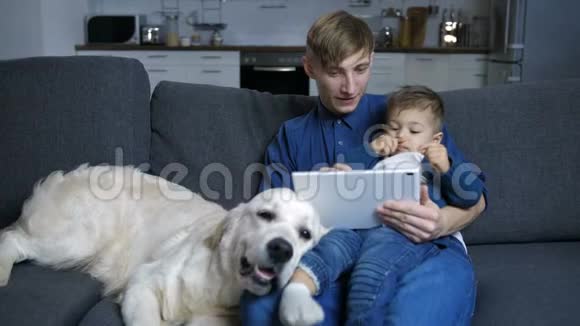 爸爸和儿子带着狗在触摸板上看动画片视频的预览图