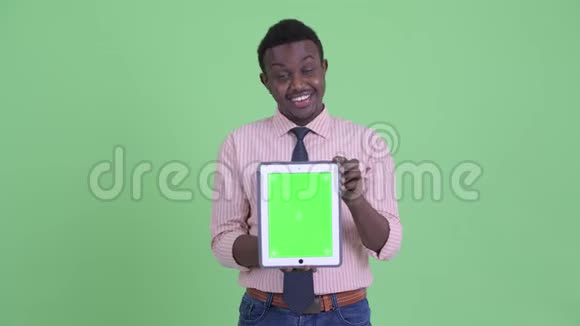 快乐的年轻非洲商人一边讲一边展示数码平板电脑视频的预览图