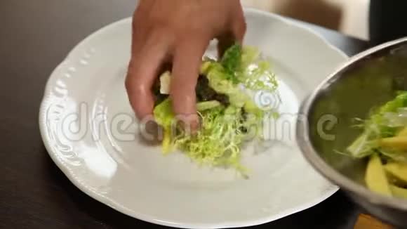 厨师把沙拉叶橘子片芒果片牛油果和橄榄油混合在盘子里视频的预览图