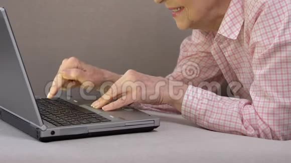 微笑的老年妇女喜欢在笔记本电脑上打字使用现代技术未来视频的预览图