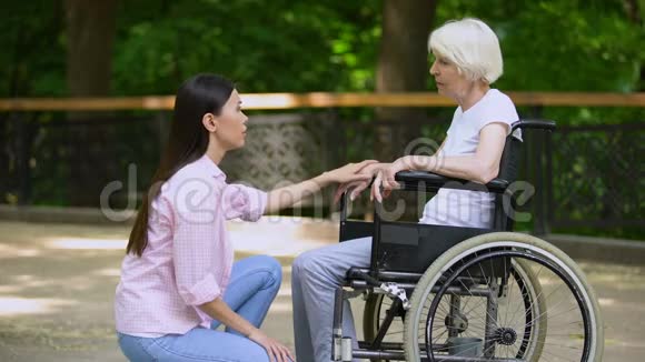 志愿者与轮椅上哭泣的女人交谈心理支持公园视频的预览图