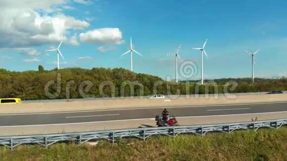旅行者站在高速公路上的摩托车上在风电场附近起飞一架无人机奥地利视频的预览图