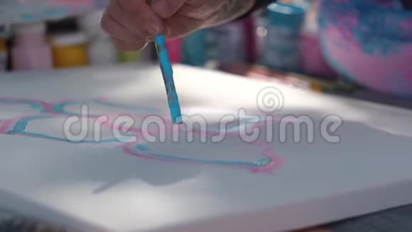 女性手拿油漆刷用蓝色和粉红色油漆工作视频的预览图