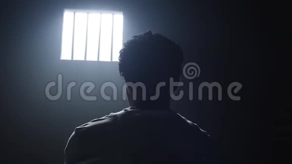 一个囚犯站在黑暗中看着监狱的窗户视频的预览图