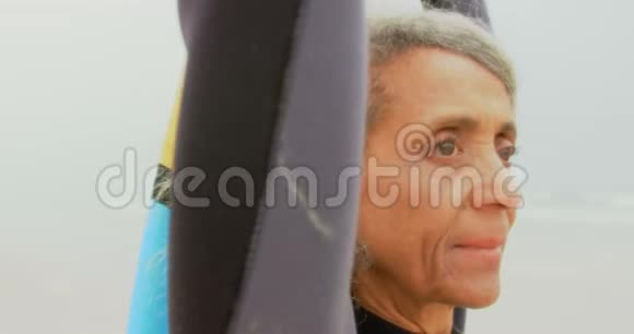 贴心体贴积极的非裔美国老年妇女冲浪板站在海滩4k视频的预览图