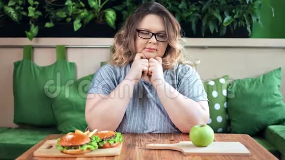 肥胖的胖女人在饮食中选择快餐和新鲜的绿色苹果中特写视频的预览图