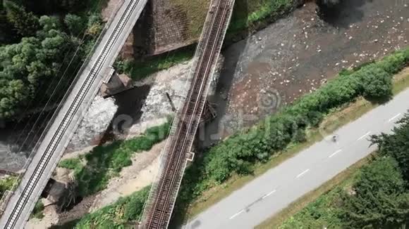 两座铁路桥梁穿过河流新旧混凝土铁路桥梁俯视图骑自行车的年轻女子视频的预览图