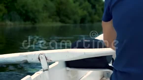 一个穿着蓝色t恤的男人在河上的小船上快速划着白色桨划着夏日视频的预览图
