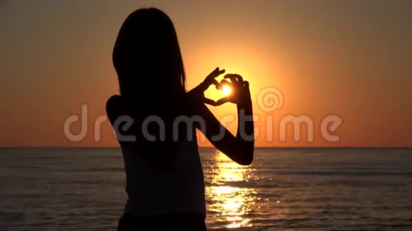 沙滩上的儿童剪影情人节日落时的爱情标志心形4K视频的预览图