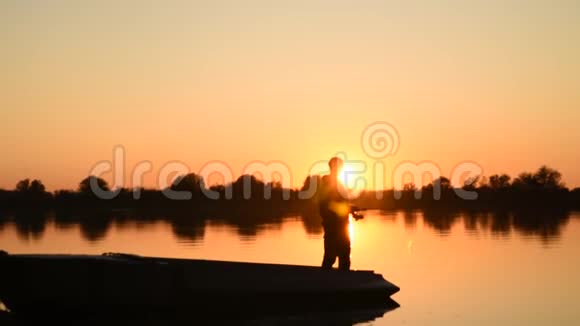 在美丽的日落中享受钓鱼的人剪影视频的预览图