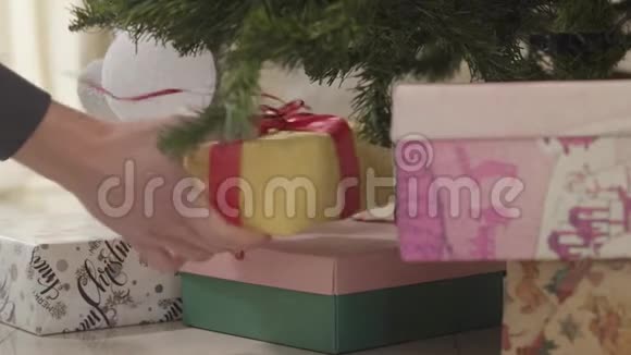 雄性白种人双手特写圣诞礼物放在新年树下在家准备度假的男人视频的预览图