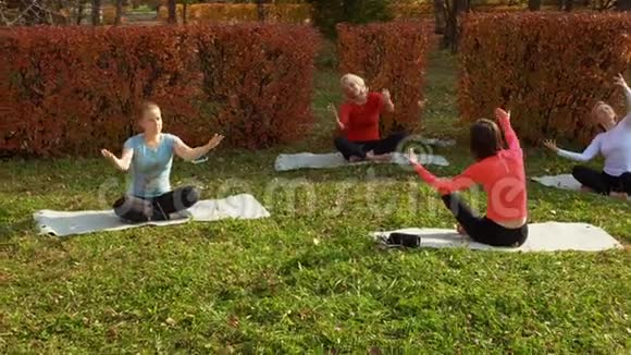 运动女性坐在垫子上在公园里练习瑜伽视频的预览图