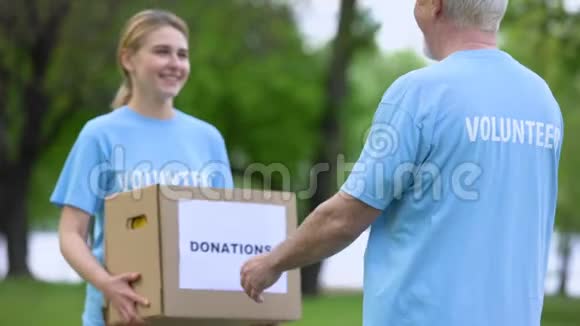 微笑青年妇女向高级志愿者捐赠捐款箱视频的预览图