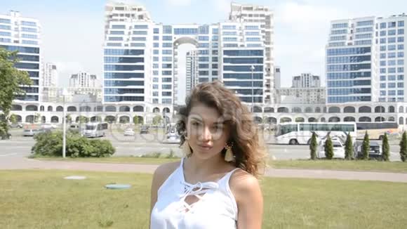 一个美丽的微笑女孩的肖像卷发背景的现代城市视频的预览图