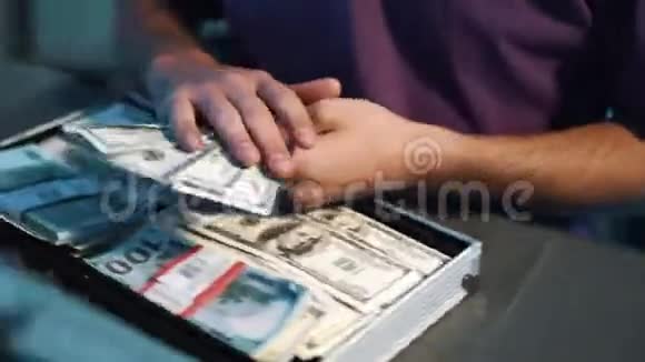 穿t恤的人把美元和其他货币放在金属手提箱里视频的预览图