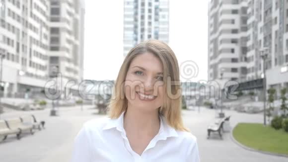女孩看着镜头微笑着在一个住宅综合体的背景下拍摄特写肖像视频的预览图