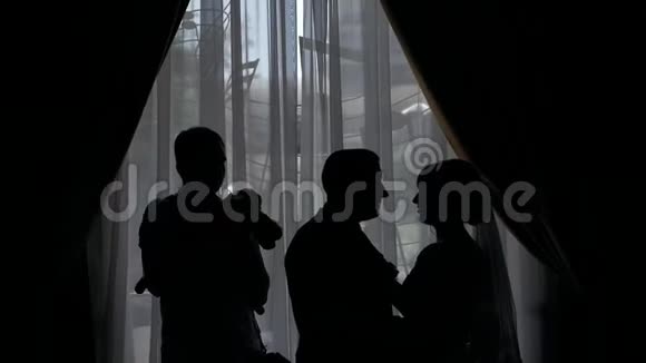 新婚夫妇穿着婚纱站在窗边的剪影视频的预览图