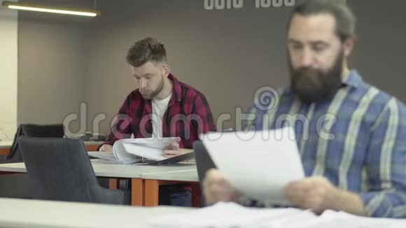 两名留胡子的办公室工作人员在办公室学习报告文件同事在工作中阅读论文视频的预览图