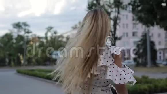 美丽的快乐女人穿着裙子在夏城小巷扔头发慢动作视频的预览图
