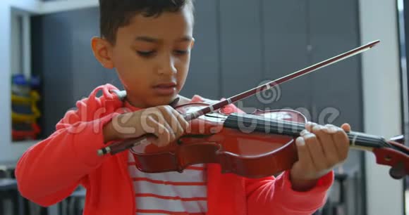 亚洲学生专心致志在4k教室拉小提琴的正面景色视频的预览图