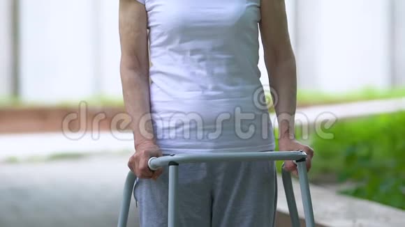 令人不安的老年妇女带着走架在室外看摄像机关节外伤视频的预览图
