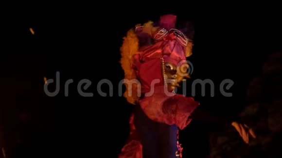 一个穿着五颜六色的服装和神秘面具跳舞的女人进入了梦乡而不是篝火视频的预览图