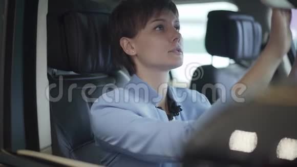 年轻漂亮女人的肖像穿着正式的蓝色西装坐在车里的前旁座椅上现代女孩选择视频的预览图