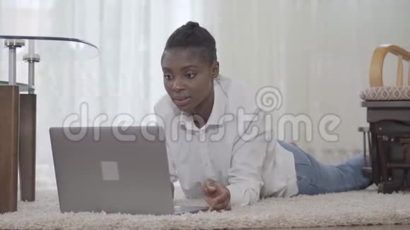 一位美国女性的肖像画很吸引人她专注于一天的工作她的笔记本电脑躺在地板上的垫子上视频的预览图