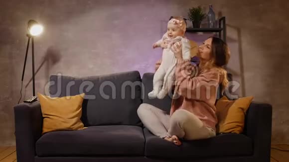 年轻的一家人坐在舒适的房间里的沙发上妈妈爸爸和宝宝一起玩家庭幸福视频的预览图