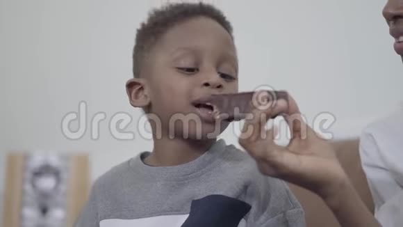 非裔美国人有魅力的妈妈和可爱的儿子一起玩给他一块巧克力蛋糕视频的预览图