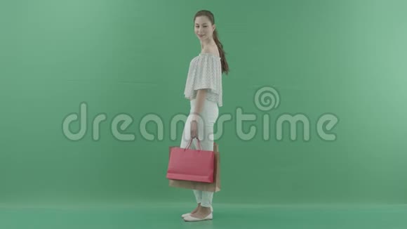 漂亮的女人拿着袋子站着看着绿色屏幕上的人视频的预览图