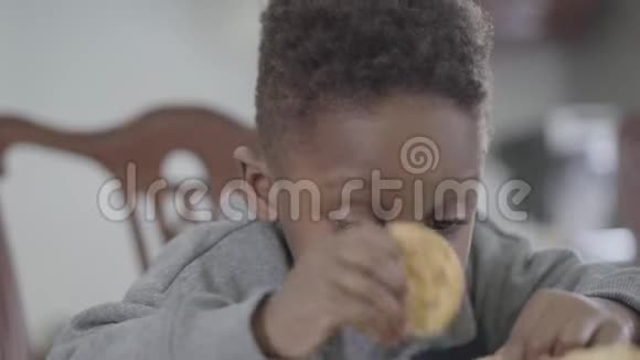 可爱的非洲裔美国儿童的肖像在牛奶后嘴唇脏兮兮坐在桌子旁玩饼干视频的预览图