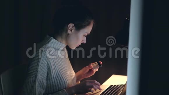 快乐的女性晚上用笔记本用信用卡购买网上购物视频的预览图
