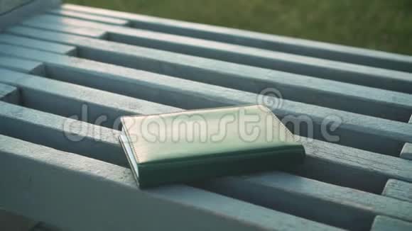 一本笔记本放在长凳上的特写女手拿笔记本视频的预览图