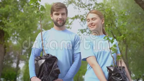 青年男女志愿者微笑镜头抱树树苗生态视频的预览图