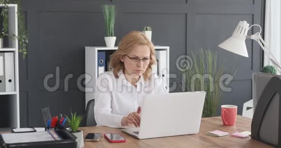 女商人从货架上拿文件在办公室里用笔记本电脑视频的预览图